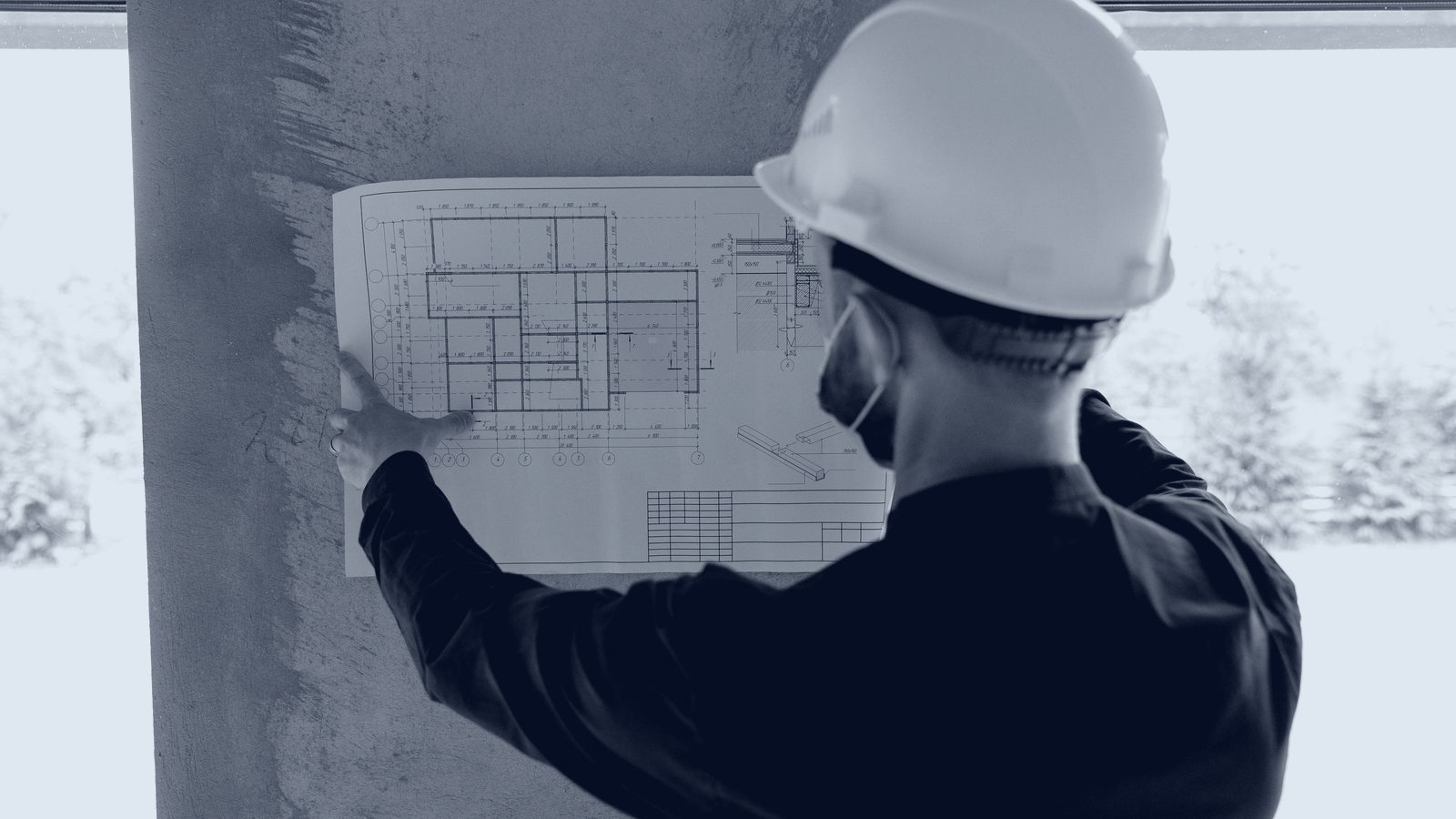Engenheiro analisando planta de projeto em obra da BYM Engenharia
